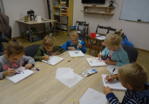 Pięcioro dzieci maluje na płótnie.